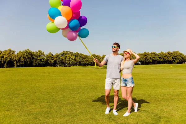 Молодий щасливий чоловік і жінка гуляють з повітряними кулями влітку да — стокове фото