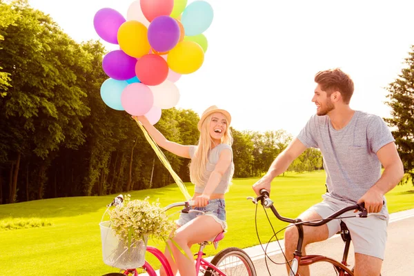 Счастливая смеющаяся пара в любви катается на велосипедах с цветами и б — стоковое фото