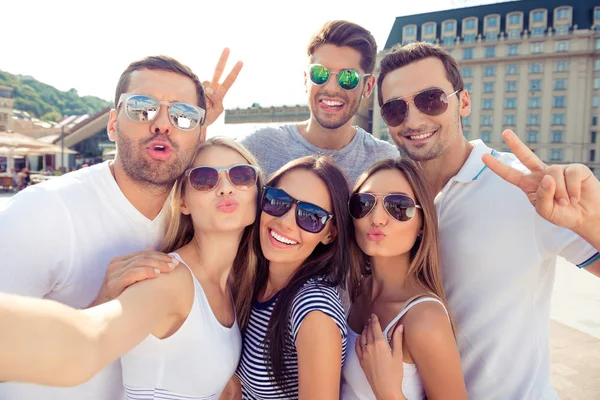 Jovens amigos felizes amamentando e gesticulando v-sign ao fazer se — Fotografia de Stock