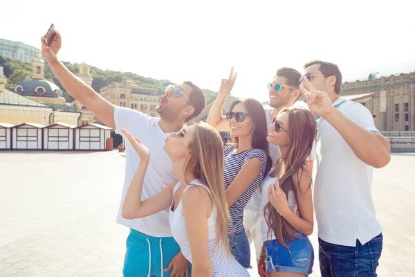 Radost chlapci a dívky chůze ve městě a dělat legrační selfie — Stock fotografie