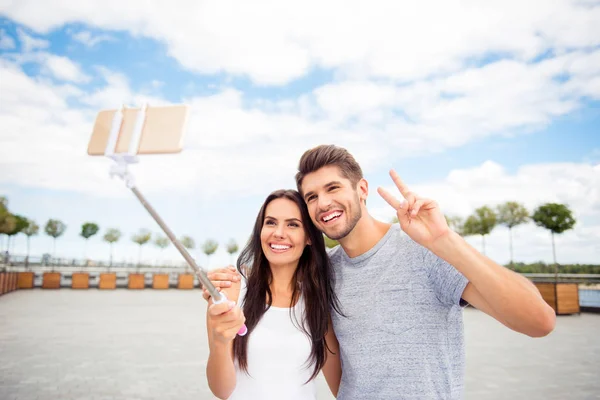 Sorrindo atraente homem e mulher fazendo selfie no monopod — Fotografia de Stock