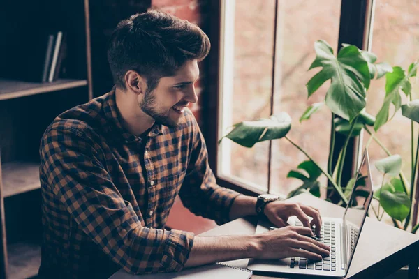 Gelukkig jonge bebaarde zakenman die op laptop in zijn kantoor te typen — Stockfoto
