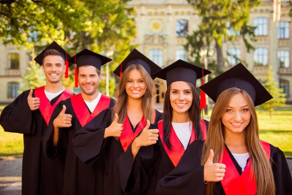 Pewny siebie pięć studentkom w szaty i kapelusze z tass — Zdjęcie stockowe