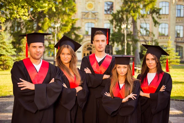 Succesvolle zeker vijf afgestudeerden in gewaden en hoeden ik permanent — Stockfoto