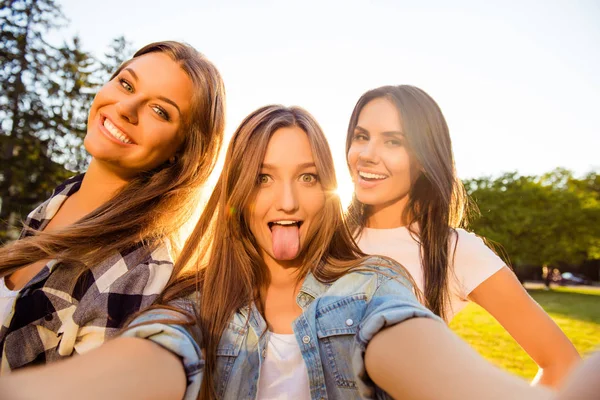 Три счастливые девушки веселятся и делают комическое селфи с языком — стоковое фото