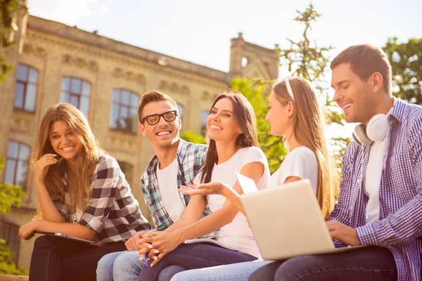 Cinque compagni di classe felici ridendo e seduti sulla panchina vicino al college — Foto Stock