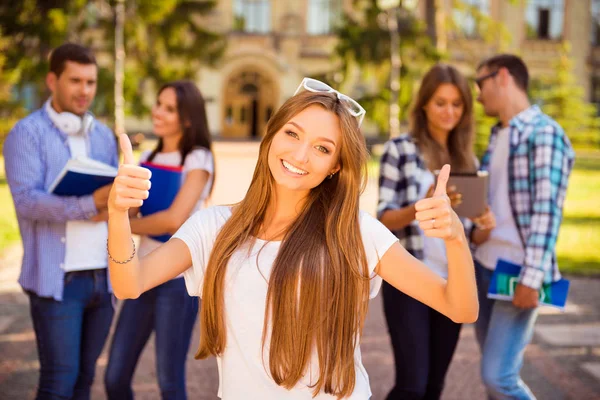 Emocionada chica feliz de pie cerca de la universidad y sus amigos y — Foto de Stock