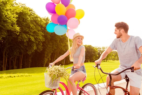 Happy lacht vrolijk paar met ballonnen paardrijden fietsen — Stockfoto