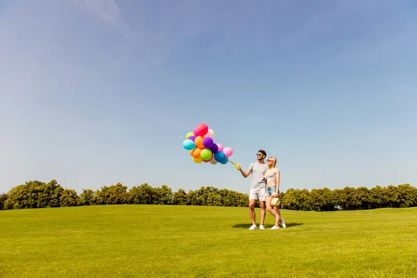 Dois amantes felizes com balões tendo data no parque — Fotografia de Stock