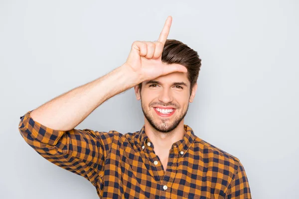 Joven divertido mostrando signo de perdedor con los dedos cerca de la cabeza — Foto de Stock