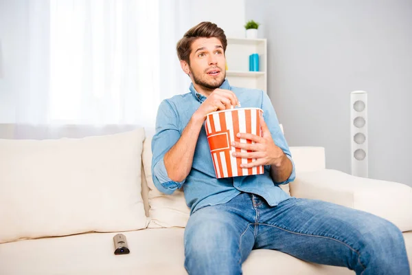 Захватывающий красивый мужчина смотрит интересный фильм с попкорном — стоковое фото