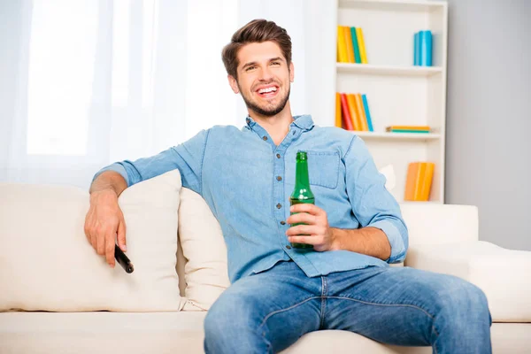 Joven hombre relajado viendo televisión y bebiendo cerveza — Foto de Stock