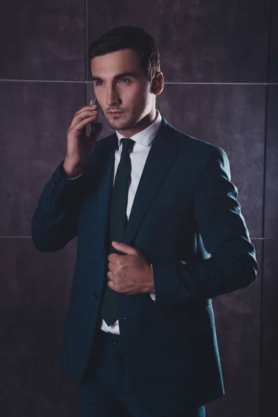 Portrait of serious young businessman talking on phone with clie — Stock Photo, Image