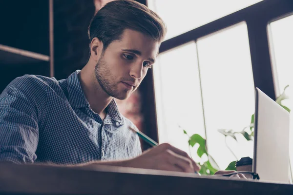 Concentrato bel giovane uomo con laptop prendere appunti — Foto Stock