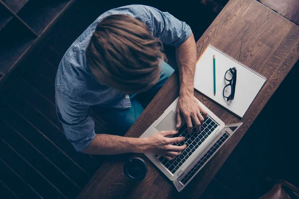 Vista dall'alto del giovane lavoratore occupato che digita sul computer portatile — Foto Stock