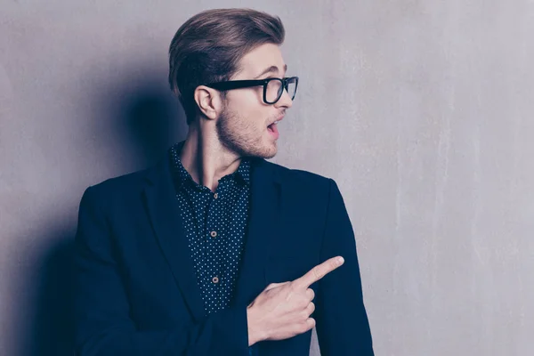 Handsome guy in glasses pointing with finger on gray background — Stock Photo, Image