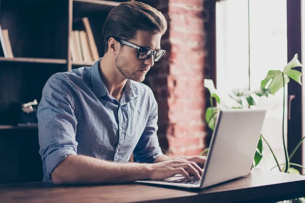Красивий концентрований молодий чоловік в окулярах друкує на ноутбуці — стокове фото