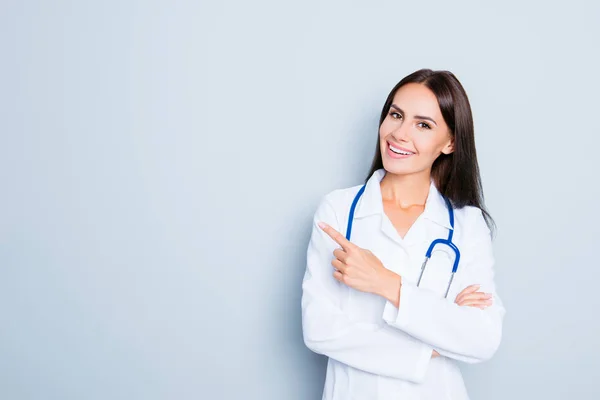 Dost gülümseyen genç kadın doktor parmak ile işaret — Stok fotoğraf