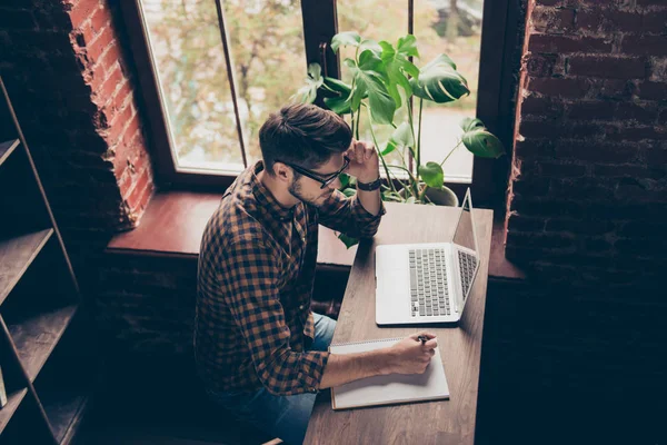 Bovenaanzicht van slimme jongen die op laptop werkt en het maken van notities — Stockfoto