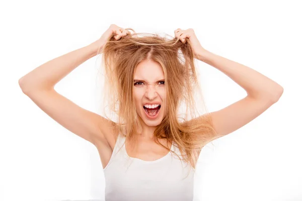 Rubia joven frustrada sosteniendo su cabello dañado y gritando — Foto de Stock