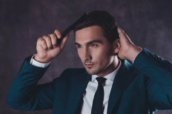 Portrait of handsome young man in black suit combing hair — Stock Photo, Image
