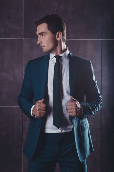 Portrait of young brutal sexy man touching his black suit — Stock Photo, Image