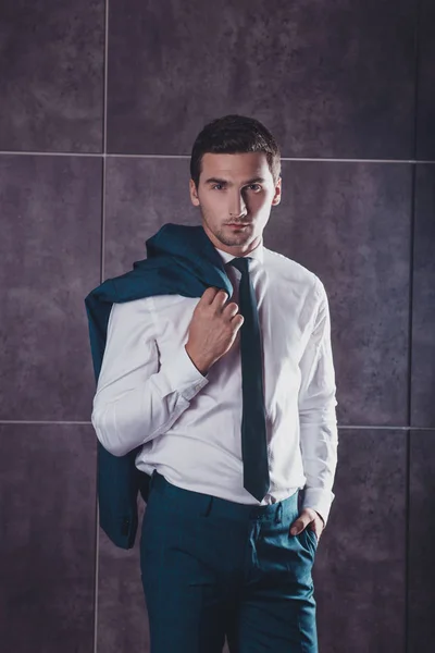 Stylischer schöner junger Mann mit Jacke auf der Schulter — Stockfoto