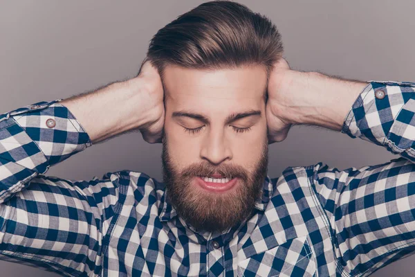 Hombre barbudo enojado con los ojos cerrados cubriendo los oídos con las manos — Foto de Stock