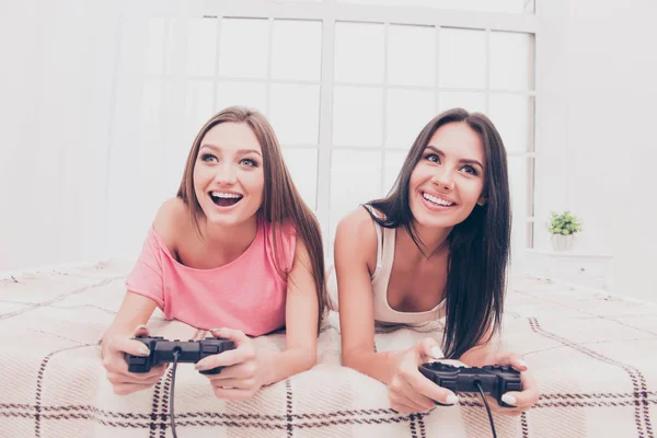 Happy opgewonden meisjes liggen in de slaapkamer en het afspelen van video game — Stockfoto