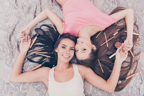 Vista superior de duas meninas bonitas deitado com cosméticos e maquiagem bru — Fotografia de Stock