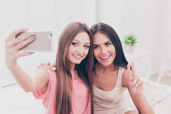 Alegres mujeres atractivas en pijamas haciendo selfie en el dormitorio —  Fotos de Stock