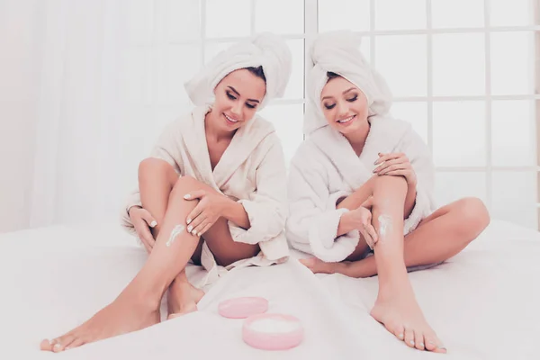 Pretty young women applying cream on their legs — Stock Photo, Image