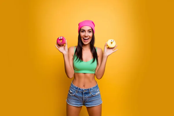 Heureuse femme élégante souriante avec des donutes isolés sur le dos jaune — Photo