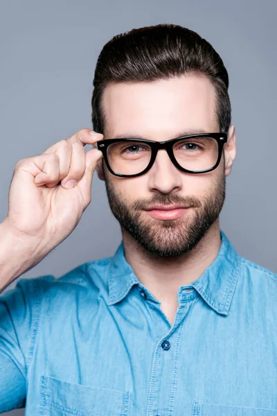 Portrét pohledného mladého seriózního muže dotýkajícího se brýlí — Stock fotografie