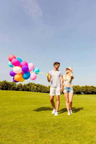 幸福小两口在爱与气球在公园散步 — 图库照片