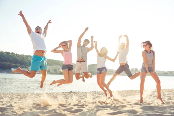 Grupo de jovens estudantes alegres felizes pulando na praia — Fotografia de Stock