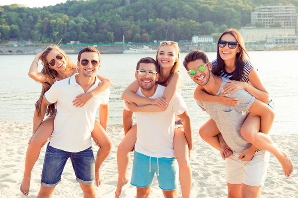 Jovens bonitos caras piggybacking suas namoradas alegres em — Fotografia de Stock