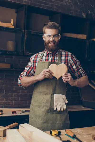 Gelukkig knap meubelmaker in de liefde bedrijf en tonen van houten hart n — Stockfoto