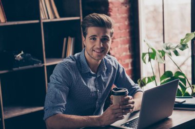 Handsome smiling man with laptop resting and drinking coffee clipart