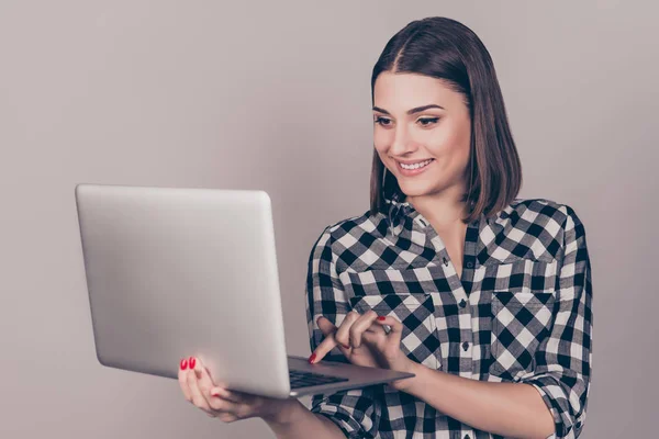 Молодая улыбающаяся брюнетка держит компьютер и печатает на нем — стоковое фото