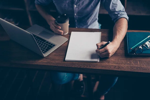 Close up van een jonge man met kopje koffie schrijven in zijn noteboo — Stockfoto