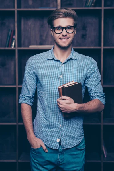 Um jovem atraente de óculos em pé na frente das prateleiras , — Fotografia de Stock
