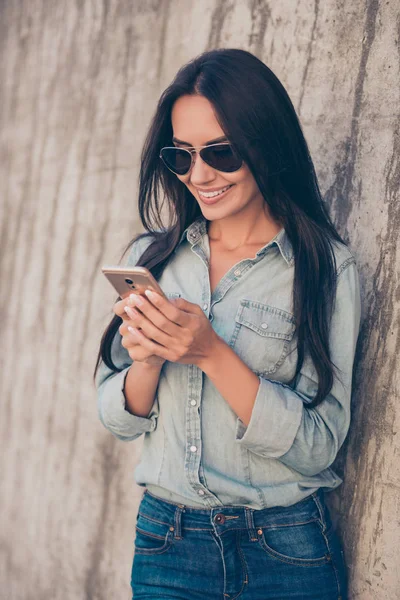 Portret van gelukkig stijlvolle brunette in glazen tuping sms — Stockfoto