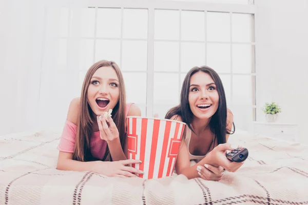 Two excited happy sisters watching film and eating popcorn — Stock Photo, Image