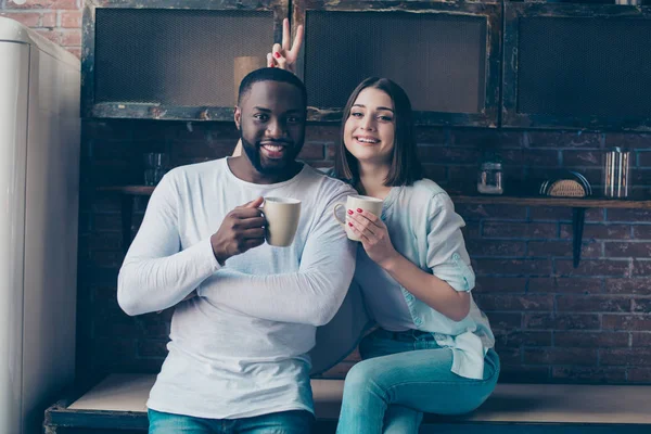 Två glada blandad ras människor dricker kaffe i köket — Stockfoto