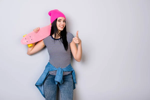 Mladá dívka v růžové čepici a skateboard na její rameno s úsměvem — Stock fotografie