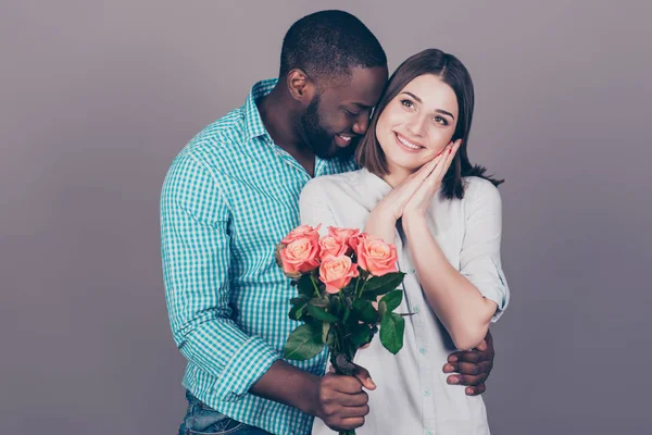 Happy afro man with roses embracing his pretty girlfriend