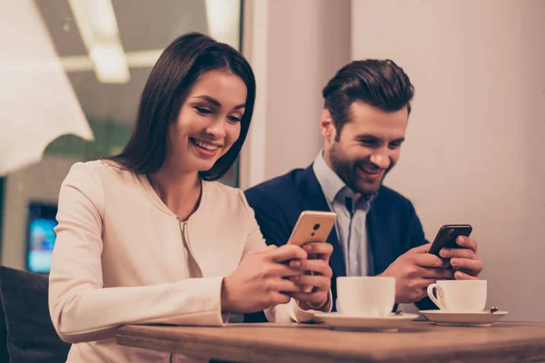 Couple joyeux assis dans un café tenant des téléphones — Photo