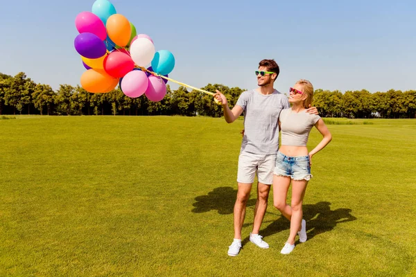 性格开朗的年轻夫妇，到户外散步与五颜六色的气球 — 图库照片