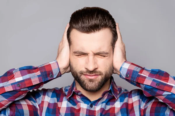 Frustrado bonito homem cobrindo seus ouvidos com as mãos em pé ag — Fotografia de Stock